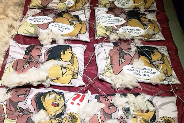 Panels of comics printed on pillows, depicting a man and a woman worried on a bed. The pillows are increasingly torn with barbed wire as the comic progresses.