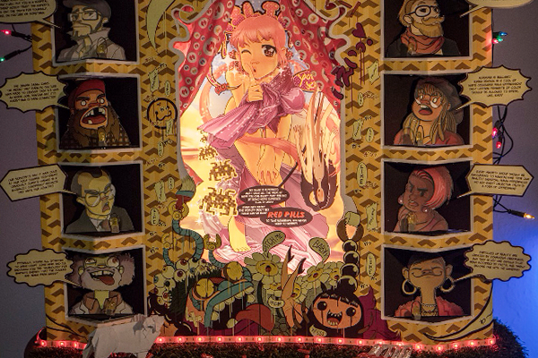 An art installation featuring a main girl character behind a curtain in the middle, illuminated by lights, surrounded by eight panels of various caricatures by her side and an origami sheep and red pills on a fake grass at her feet.