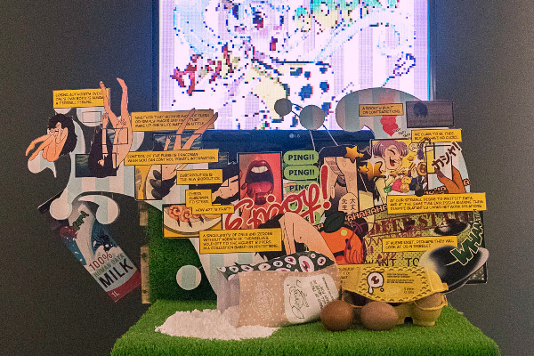Comic panels flow out of a milk carton while flour and eggs lay in the foreground on custom-made packaging. A screen shows a pixelated image of a woman with an apron shouting "Oops!" while spilling her things in the kitchen.