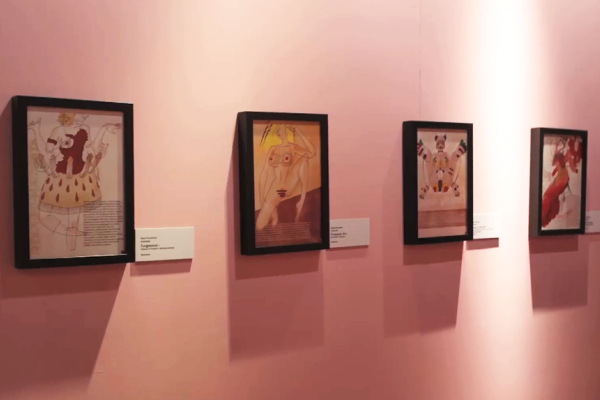 A framed digital print of four concept sketches hanging on a light pink wall.